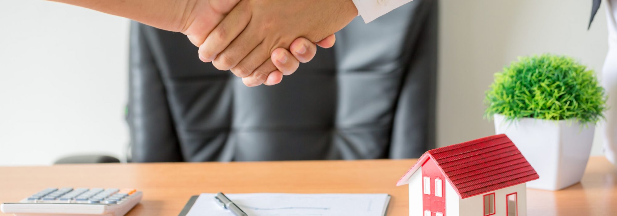 Side view hands of agent and client shaking hands after signed contract buy new apartment.